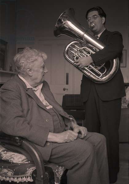 1547090 Composer Ralph Vaughan Williams listens to tuba player Philip Catelinet in his Regent's Park apartment (b/w photo); (add.info.: Composer Ralph Vaughan Williams listens to tuba player Philip Catelinet who is playing the solo part of Williams' Concerto for Tuba and Orchestra in F Minor, a work dedicated to Catelinet and first performed in the early 1950's. A recording of this work dating from 1954 exists.); © Brian Seed. Please note: Bridgeman Images represents the photographer and clear the copyright on your behalf. A Premium fee will be added to your quote/invoice. Please contact Bridgeman Images for further information.